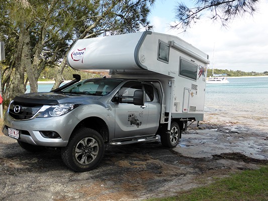 Ozcape Slide-On motorhome Woondabaa in front of ocean bay with crystall clear turquoise water