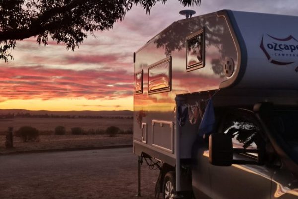 Ozcape camper at sunset in the bush with the stunning colours of the skies refelected in the shiny walls of the Slide-On